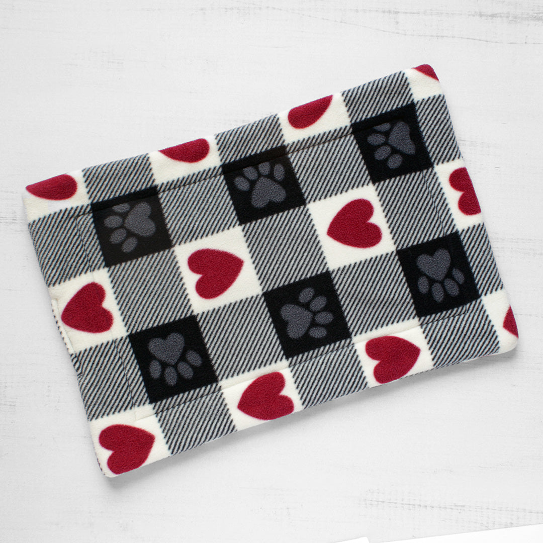 Top view of cat mat in red, white, and black squares. Some squared have red hearts and some have gray paws.