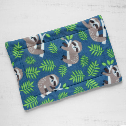 Top view of cat mat showing cute brown sloths and green leaves on blue background.