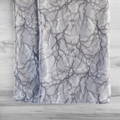 Dog blanked hanging up showing both sides printed with medium grey and white branches pattern on light grey background.