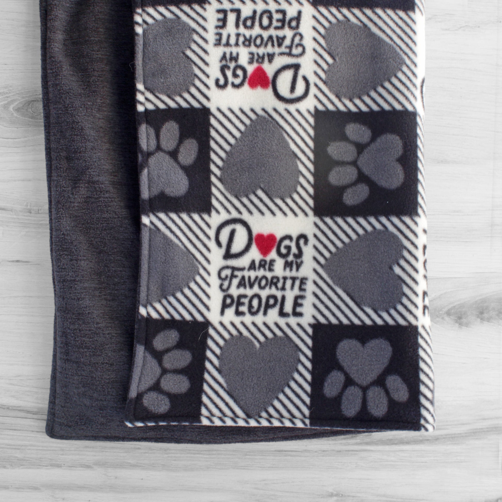 Dog blanket hanging up with dark grey and white checkerboard pattern. Some squares have grey hearts or paw prints, and others have text that says dogs are my favorite people. Back side if dark heather grey.