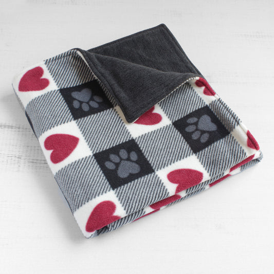 Dog blanket folded up with red, white, and black squares. Some squared have red hearts and some have gray paws. Back side is solid dark heather grey.