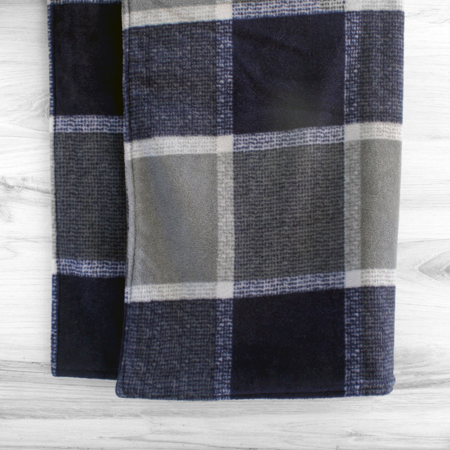 Dog blanket hanging up with navy and grey plaid pattern on both sides.