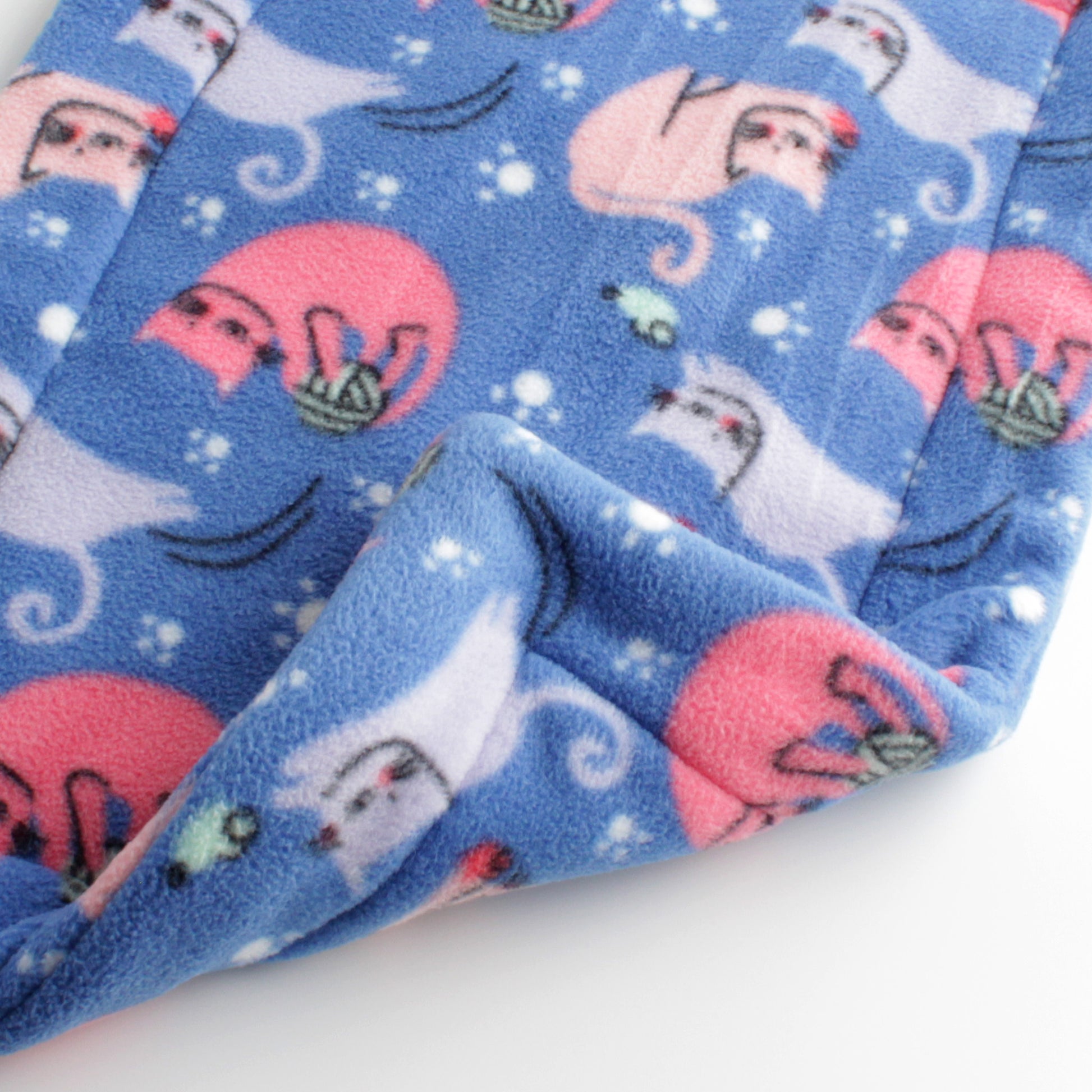 Closeup of cat mat with pink and blue cats playing with toys on a blue background. Print is same on both sides of the mat.